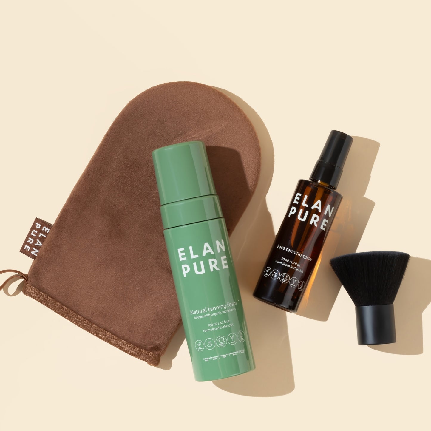 Elan Pure tanning products including a self-tan bottle, face tanning mit, brush, and tanning mitt on a beige background.